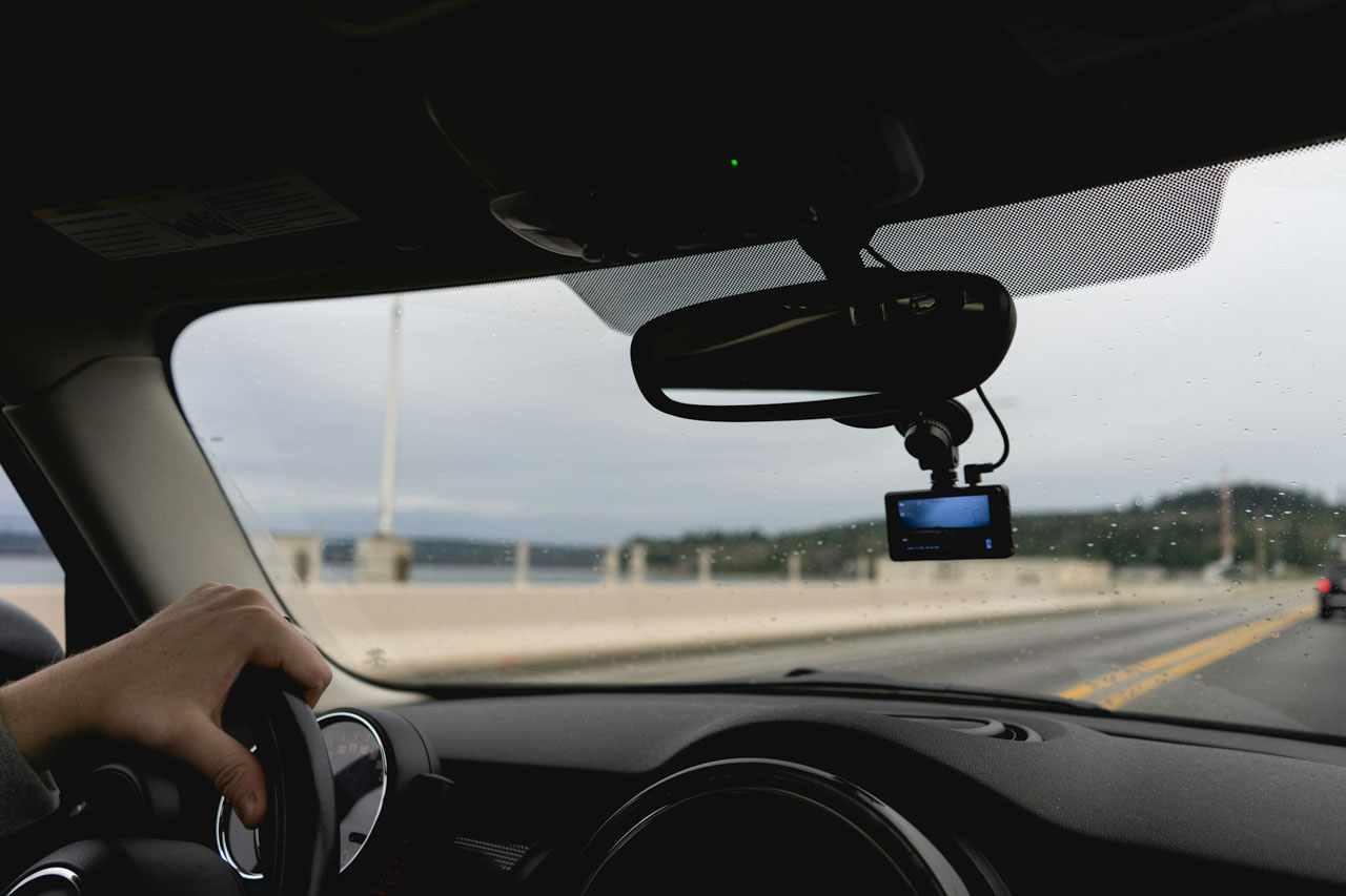 A dashcam recording footage on a car dashboard during a road journey.
