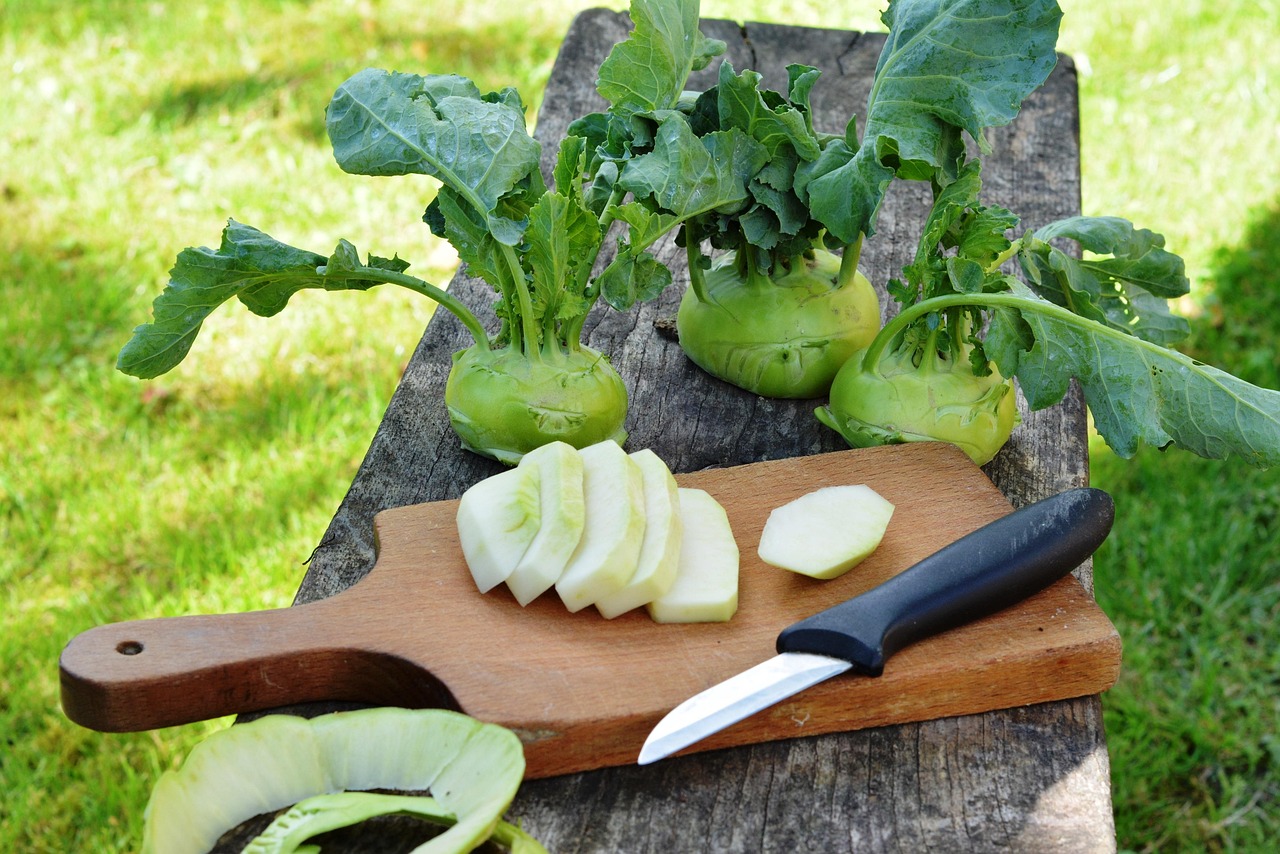 Fresh kohlrabi from the garden, with some sliced on a board next to a knife
