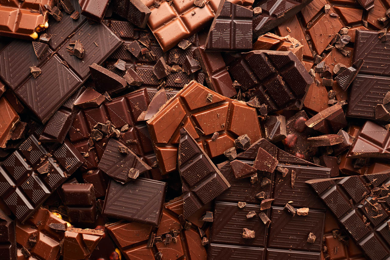 A close-up image of different varieties of gourmet chocolate bar, some broken up.