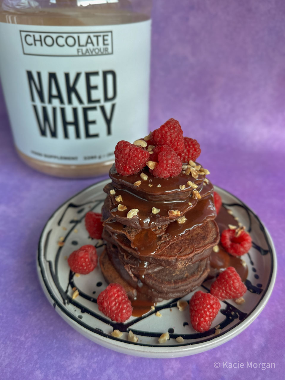 Chocolate protein pancakes topped with raspberries and chocolate sauce