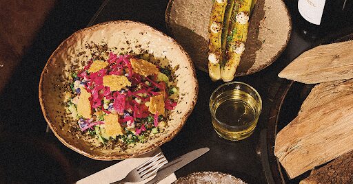 A healthy, vibrant salad next to a glass of water and some bread