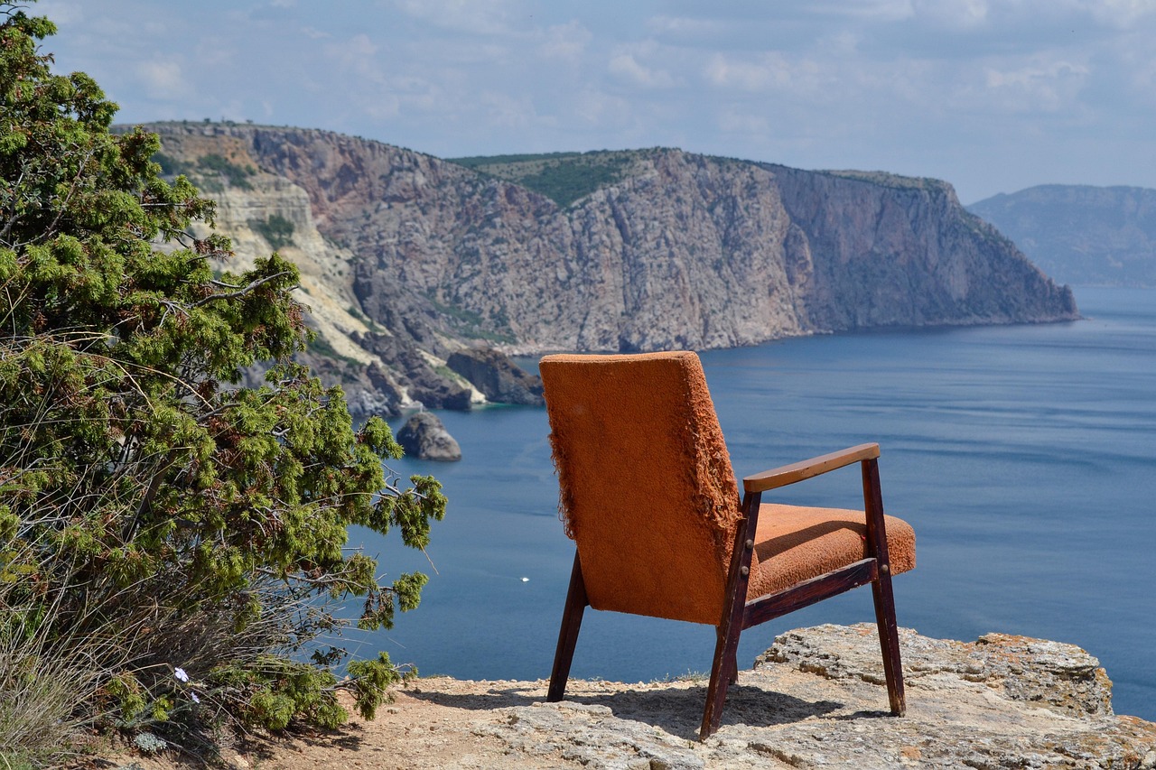 An armchair sitting on the edge of a cliff with a coastal cliff scene in the background.