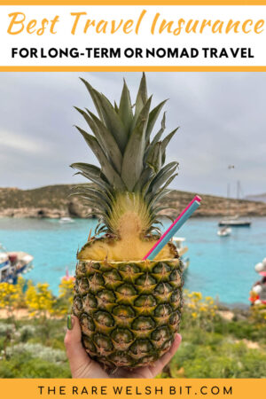 A cocktail in a pineapple, against a backdrop of aqua blue sea and natural vegetation in Comino, Malta