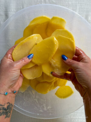 Coating the potato slices in melted butter