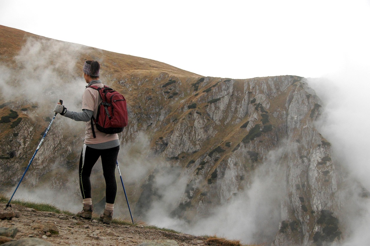 A lady hiking ona mountain with walking sticks.