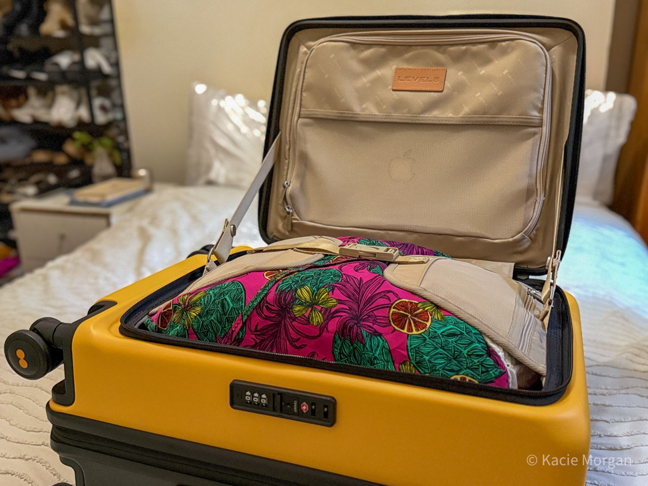 The Adventure Carry On 20", pictured open filled with folded clothes and an Apple Macbook in the laptop compartment.