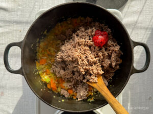 Return the browned mince to the pan with the softened onion, celery and carrot, and add the tomato puree.