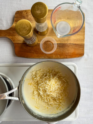 Making roux: once the milk, butter and flour mixture has thickened, stir in grated cheese before adding nutmeg, salt and pepper.