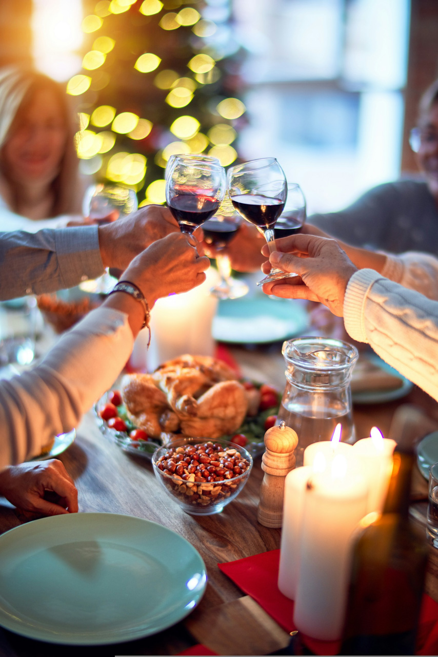 Hands raising glasses in a toast, over a festive table arrangement